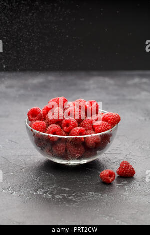 Photo of fresh raspberries in transparent glass cup on black background Stock Photo