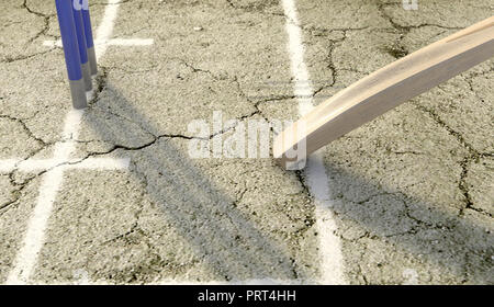 A tip of a cricket bat sliding over the crease on a cracked grass pitch background - 3D render Stock Photo