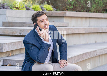 Attractive, modern businessman talking and texting on his phone. Successful entrepreneur doing work. Stock Photo