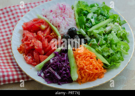 Fresh mixed vegetables salad. Selective focus,top view.There are tomatoes, lettuce, onions, radishes, carrots, purple cabbage, olives and cucumbers. Stock Photo