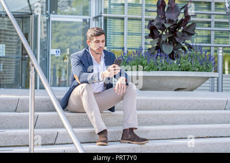 Attractive, modern businessman talking and texting on his phone. Successful entrepreneur doing work. Stock Photo