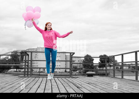 Young girl holding pink balloons and waiting for her birthday party Stock Photo