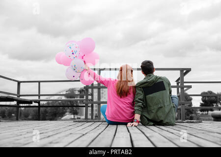 Two people sitting on the pier close to each other Stock Photo