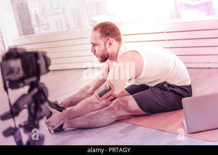 Concentrated skilled trainer doing morning exercises at home Stock Photo