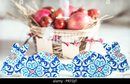 Paper Easter rabbits on the background of baskets of eggs, the concept of the Easter holidays and homey decor Stock Photo