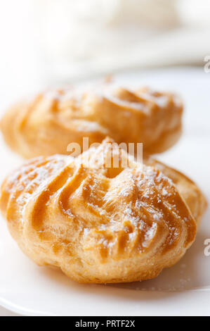 Fresh eclairs with cream on white plate. Stock Photo
