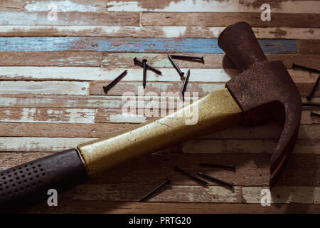 Rusty hammer with nails on a grunge wood background. Stock Photo