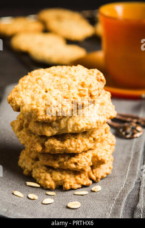 Stack of homemade oatmeal cookies on tissue with cup of tea or coffee, vertical shot Stock Photo