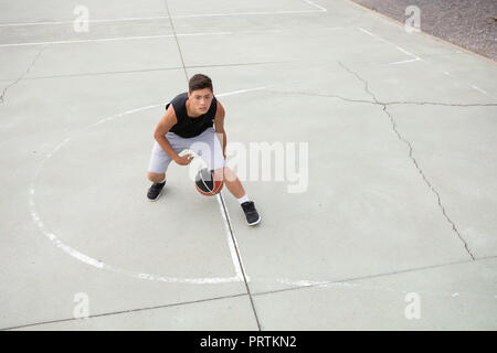 Male teenage basketball player practicing on basketball court, high angle view Stock Photo