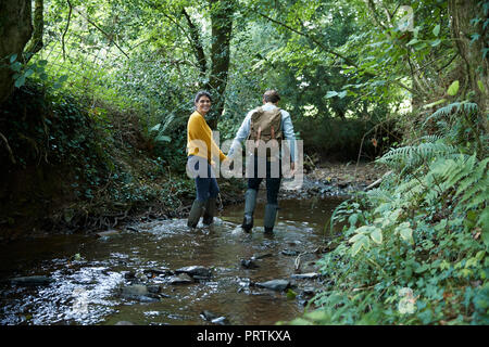 Hiker couple walking in stream Stock Photo