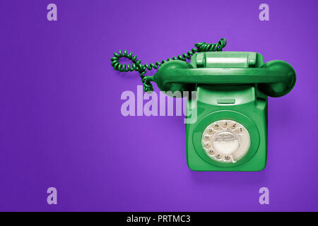 Green rotary phone from above on a purple background Stock Photo