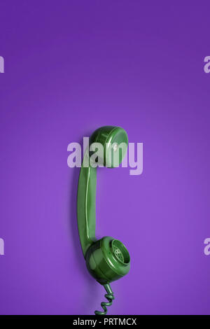 Retro green rotary phone handset on a vibrant coloured background with space for copy and text Stock Photo