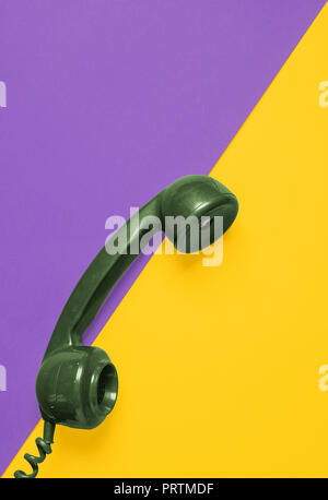 Retro green rotary phone handset on a vibrant coloured background with space for copy and text Stock Photo