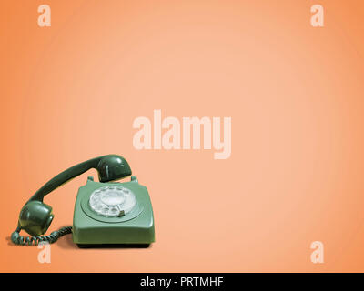 Retro green rotary phone on a vintage orange background with space for copy and text Stock Photo