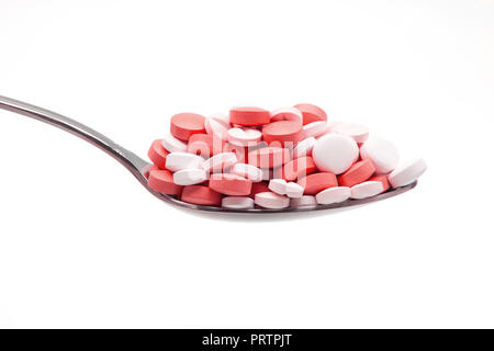 Red pills on spoon isolated on white Stock Photo