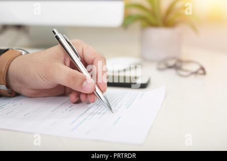 Man is filling a form with pen in left hand. Stock Photo