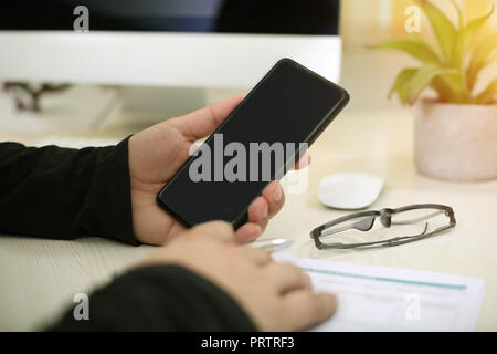 Portrait of filling form with pen. Portrait man showing phone in hand with glasses and wireless mouse on table. Stock Photo