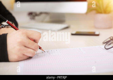 Man is putting sign on OMR sheet with pencil. Stock Photo