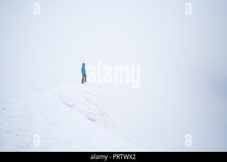 Mountain hiking in the winter. Landscape with snow and fog. Tourist stands on top Stock Photo