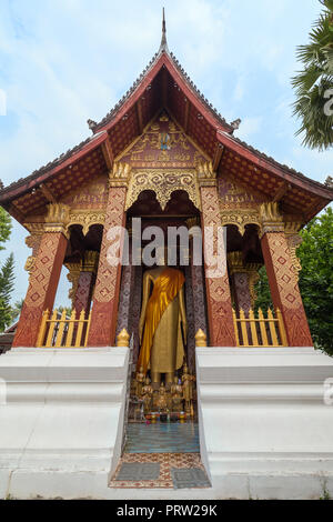 Big golden statue of standing Buddha at the Vat Sensoukharam (Sene Souk Haram) Temple in Luang Prabang, Laos, viewed from the front. Stock Photo