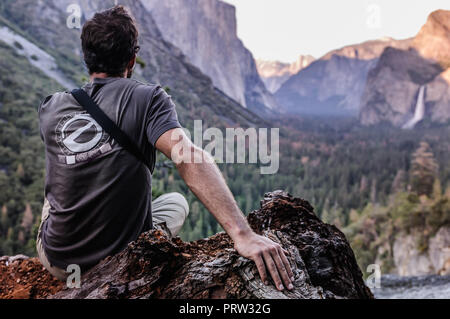 Rock climber looking out at mountain ranges, Yosemite National Park, California, USA