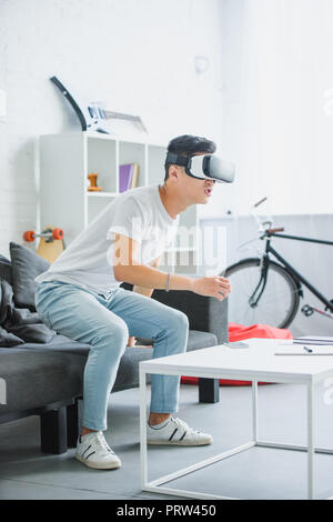 emotional young asian man using virtual reality headset at home Stock Photo