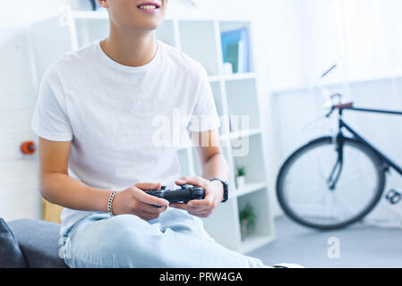 cropped image of smiling man playing video game on sofa at home Stock Photo