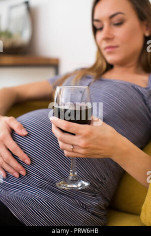 Concerned Pregnant Woman Drinking Red Wine At Home Stock Photo