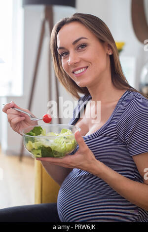 Portrait Of Pregnant Woman Eating Healthy Salad At Home Stock Photo