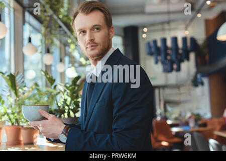pensive businessman in suit with cup of coffee having coffee break in cafe Stock Photo