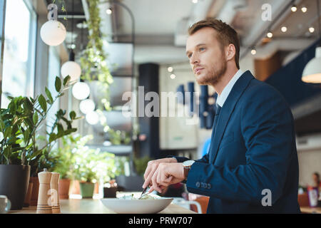 side view of thoughtful businessman looking away while having lunch in cafe Stock Photo