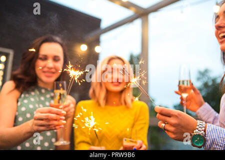 Group of partying girls with flutes with sparkling wine and bengal fire having fun on the party Stock Photo