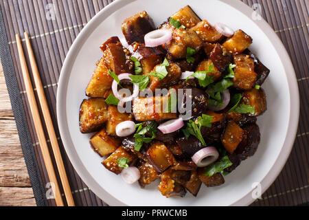 Chinese style eggplants in spicy soy sauce with ginger, garlic, pepper, closeup on a plate on the table. horizontal top view from above Stock Photo