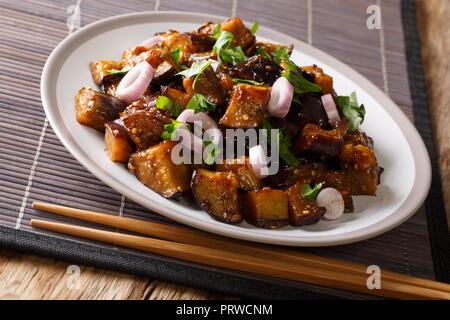 Sichuan Style Braised Eggplant With ginger, garlic, pepper and suy sauce closeup on a plate on the table. Horizontal Stock Photo