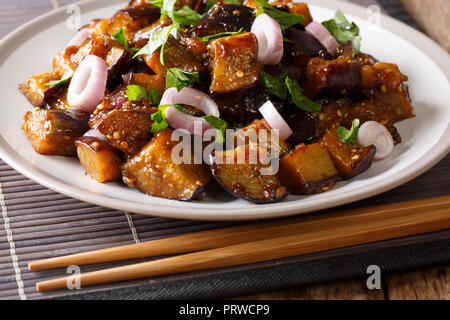 Chinese style eggplants in spicy soy sauce with ginger, garlic, pepper, closeup on a plate on the table. horizontal Stock Photo