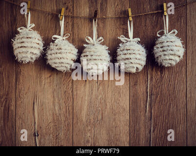 Christmas decorations white textile snowballs on the wooden background. Christmas decorations, toys for the Christmas tree hanging on clothespins. Cop Stock Photo
