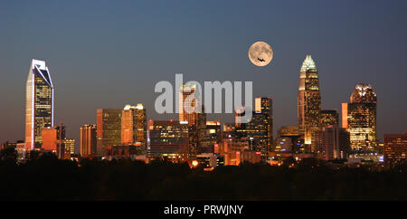 Skyline of Charlotte, North Carolina, at sunset with a full moon overhead. Stock Photo