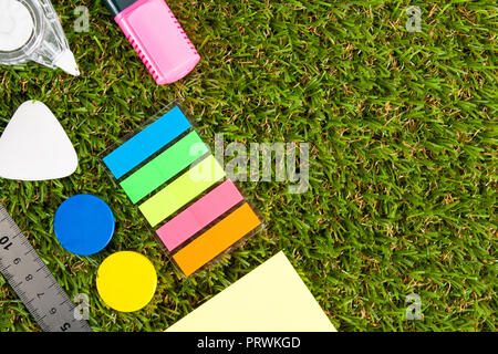 Office supplies lie on green artificial grass. Flat lay. Stock Photo