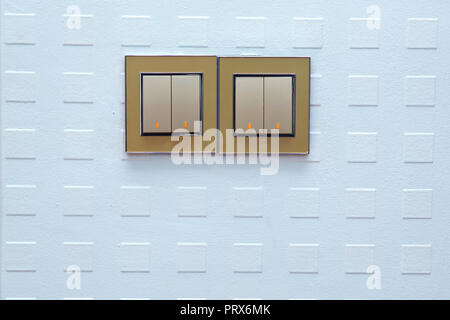light switch, turn on or turn off the lights . a light switch, a plastic mechanical switch of white color installed on a light gray wall. Light switch Stock Photo