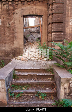 Steps in front of the entrance in old abandoned brick building with ruined walls inside Stock Photo