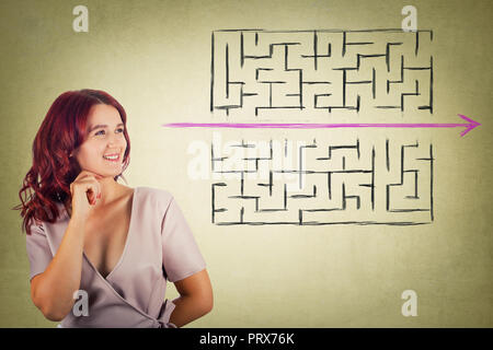 Young redhead pensive woman holding hand under chin thoughtful looking to find a solution to escape from maze. Young businesswoman breaking the rules, Stock Photo