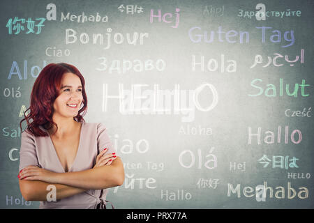 Confident young woman with crossed arms say hallo in different languages. Opportunity for learning new languages for students. Stock Photo