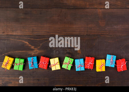 Colorful presents in line over wooden background with copy space; overhead view Stock Photo