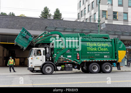 Green clean energy solid waste management garbage truck lifting a dumpster, Vancouver, BC, Canada Stock Photo