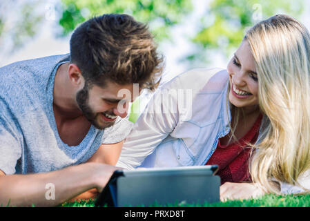 Couple using digital tablet in park Stock Photo