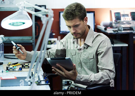 Engineer soldering circuit board in office Stock Photo