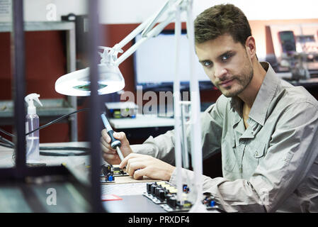 Portrait of engineer soldering circuit board in office Stock Photo
