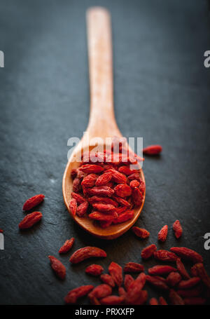Close-up of dried goji berries in wooden spoon on dark background Stock Photo
