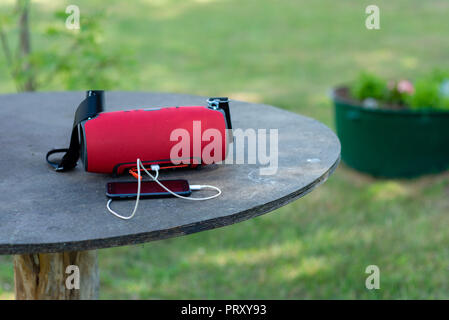 Smartphone with portable speakers is placed on a wooden table. Stock Photo