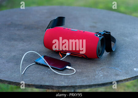 Smartphone with portable speakers is placed on a wooden table. Stock Photo